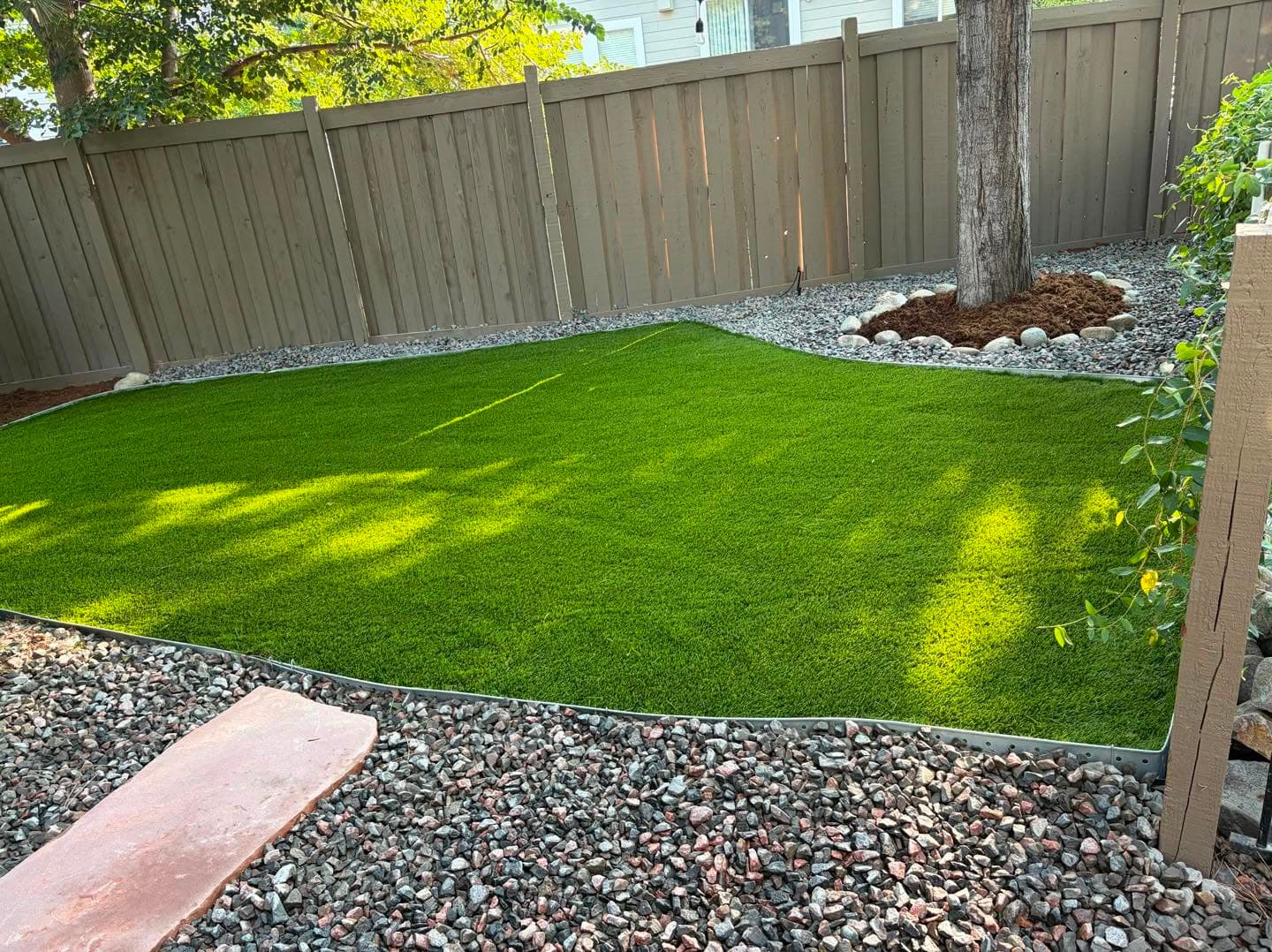 Residential landscape with artificial turf, mulch beds, and gravel borders