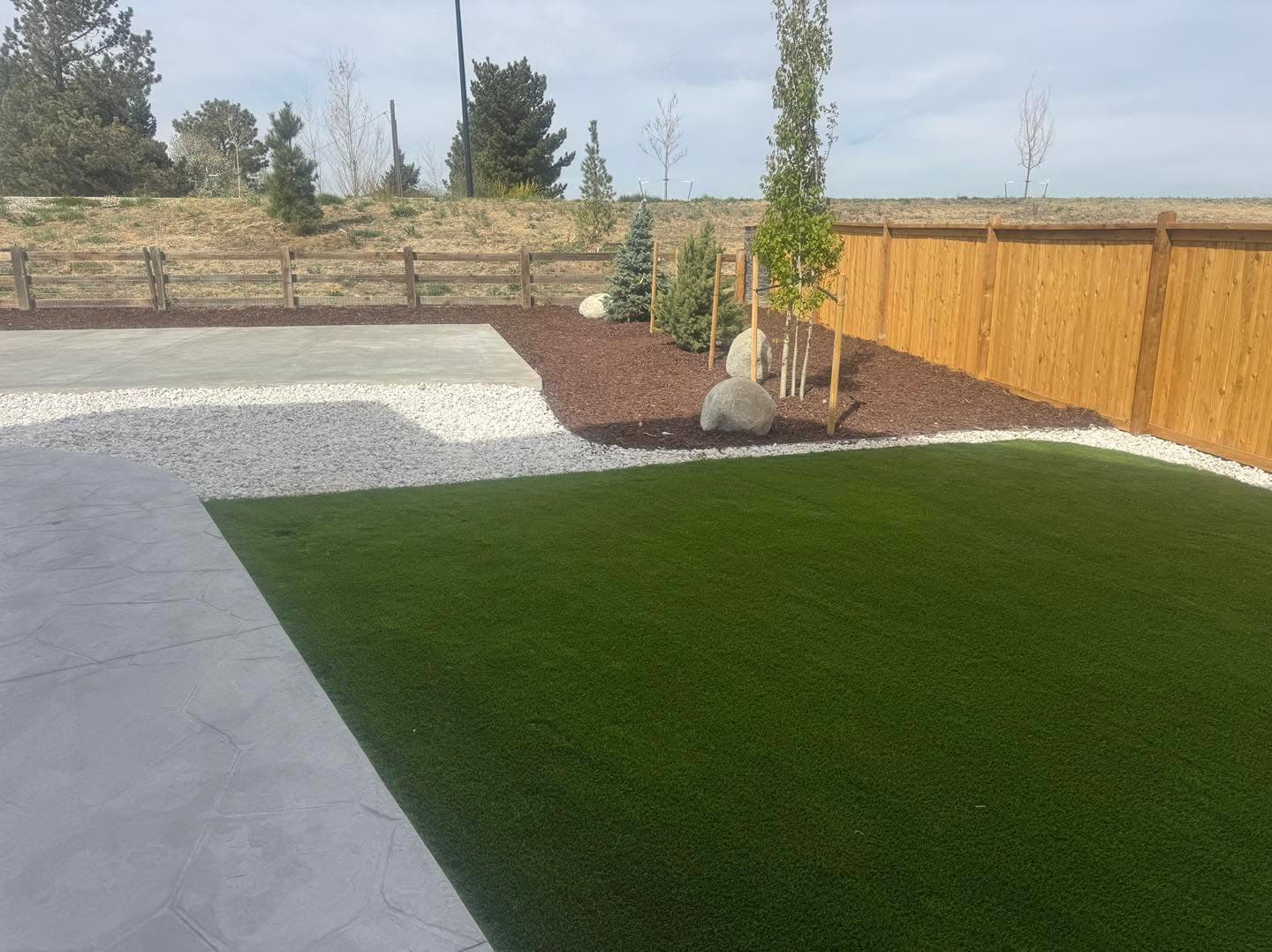 Artificial turf with concrete patio and gravel planting beds
