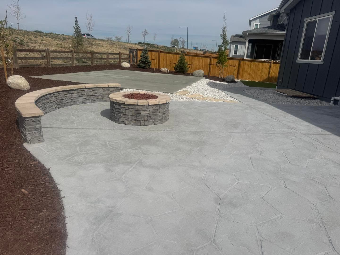 Concrete patio with curved fire pit feature and gravel accents