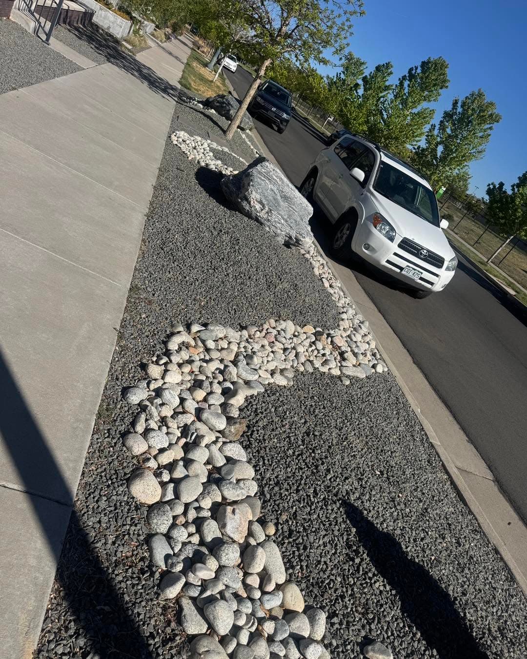 Complete residential landscape with gravel beds, concrete curbing, and white stones