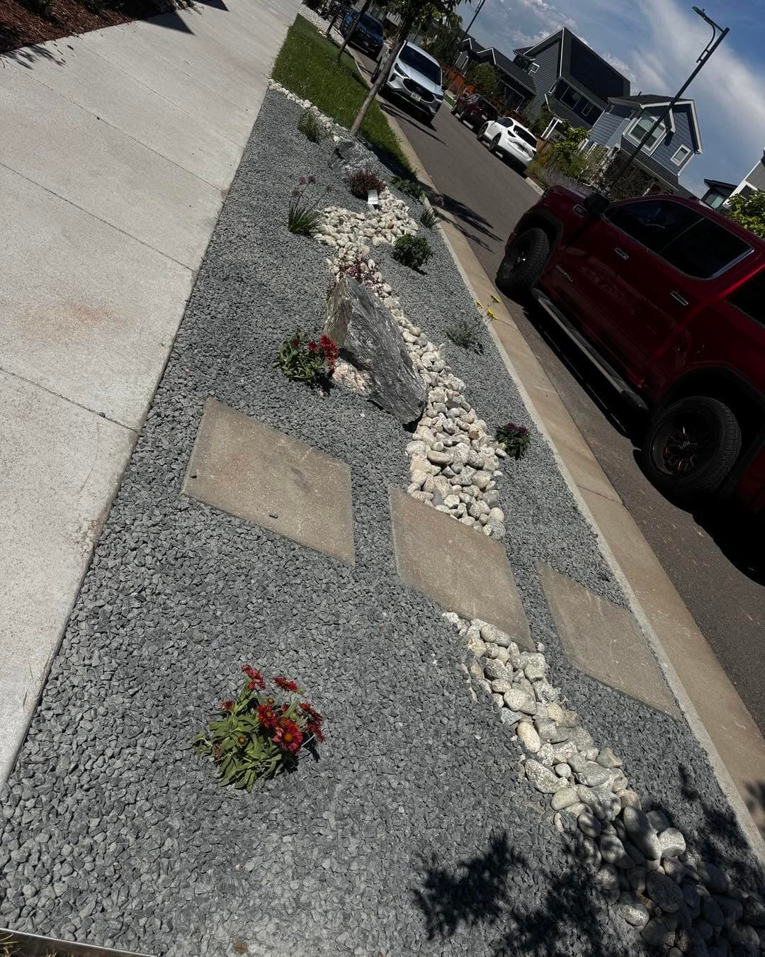 Gravel beds with white river stones, red flowering plants, and concrete pavers