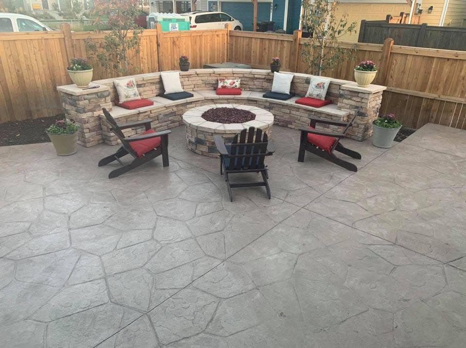 Backyard patio with stained concrete, brick fire pit, built-in seating, and lush landscaping